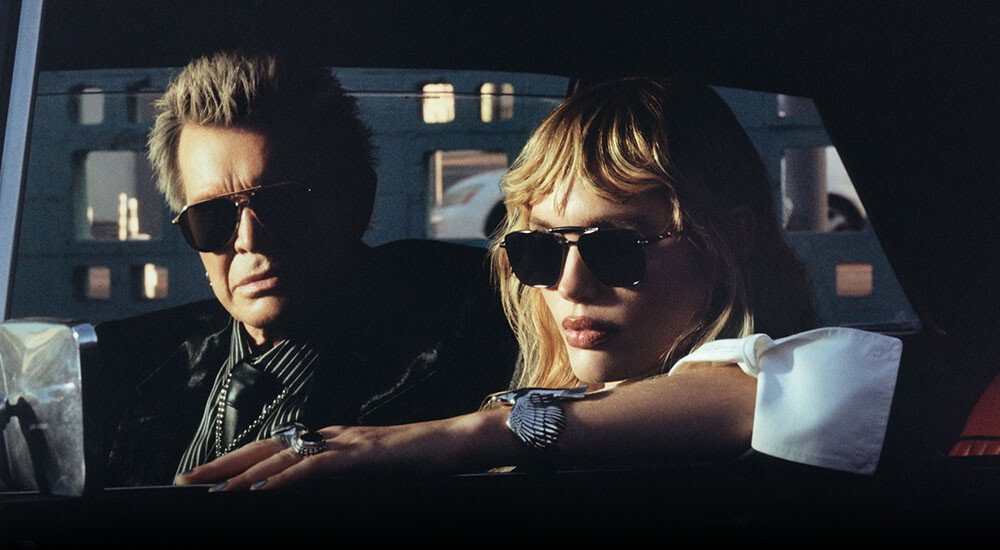 An Image of Billy Idol (left) wearing The Great Frog Limited-Edition Triumph Aviator Sunglasses in Black/Gold and Staz Lindes (right) wearing The Great Frog Capri Rectangular Sunglasses in Gun Metal/Black