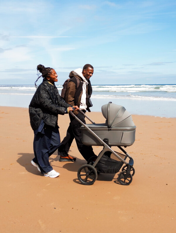 Image of a couple walking on the beach with their Cove 2 Travel System